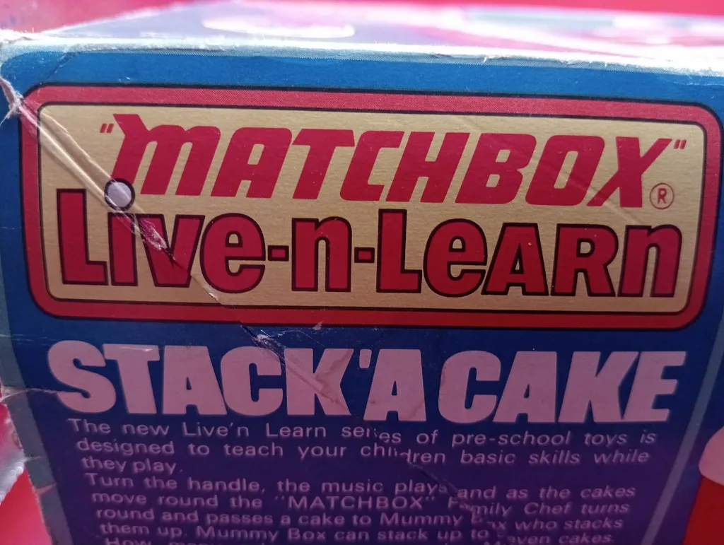 ouet Matchbox Stack‑a‑Cake vintage – boîte d’origine – jouet musical à plateau tournant – éléments roses et orange – état fonctionnel avec aide au mouvement