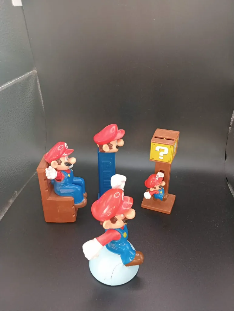 Lot de 4 objets Mario – figurines en plastique rouge et bleu – personnage assis, tête sur support bleu, bloc point d’interrogation et figurine sur socle blanc