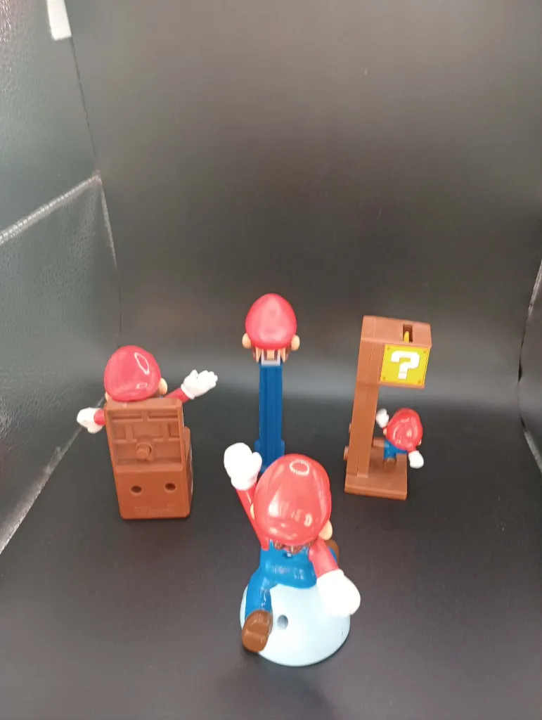 Lot de 4 objets Mario – figurines en plastique rouge et bleu – personnage assis, tête sur support bleu, bloc point d’interrogation et figurine sur socle blanc