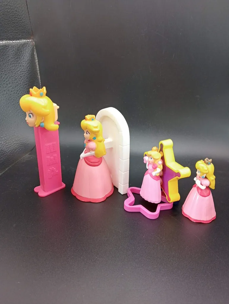 Lot Princesse Peach – figurines en robe rose avec couronne dorée – figurine devant arche blanche – figurine sur support étoile rose et jaune – tête Peach sur support rose