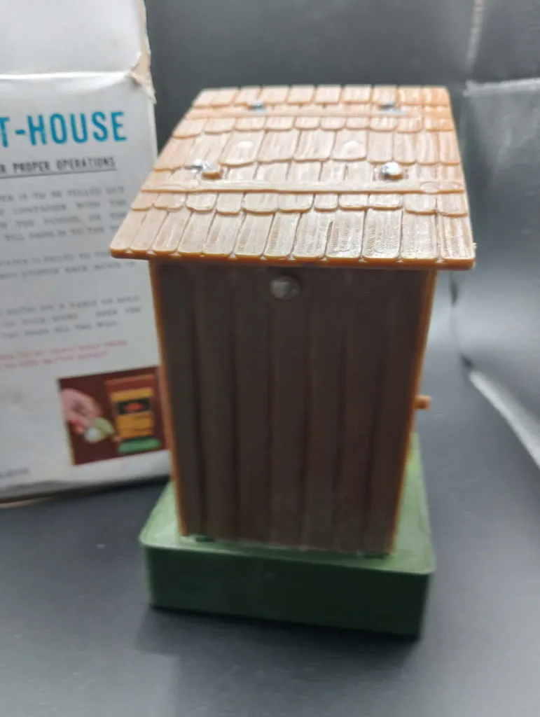 Jouet gag mécanique vintage The Out-House No. 606 en plastique, cabane brune avec personnage intérieur, réservoir d’eau et boîte d’origine