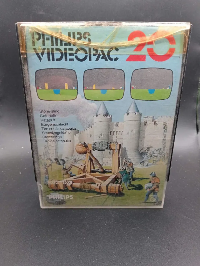 Jeu rétro Philips Videopac 20 Stone Sling de 1980 avec cartouche noire, boîtier rigide illustré d’une catapulte médiévale et livret d’origine