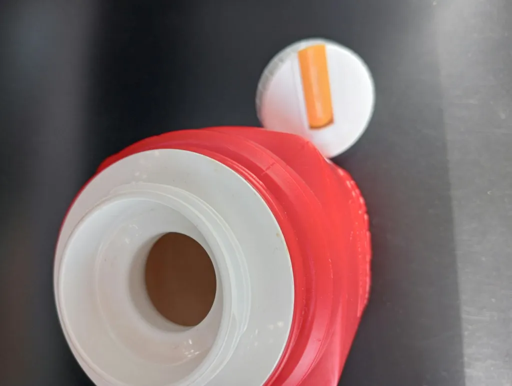 Red vintage Roughneck thermos with Snoopy and Woodstock, white stopper with orange flip tap and missing outer cup