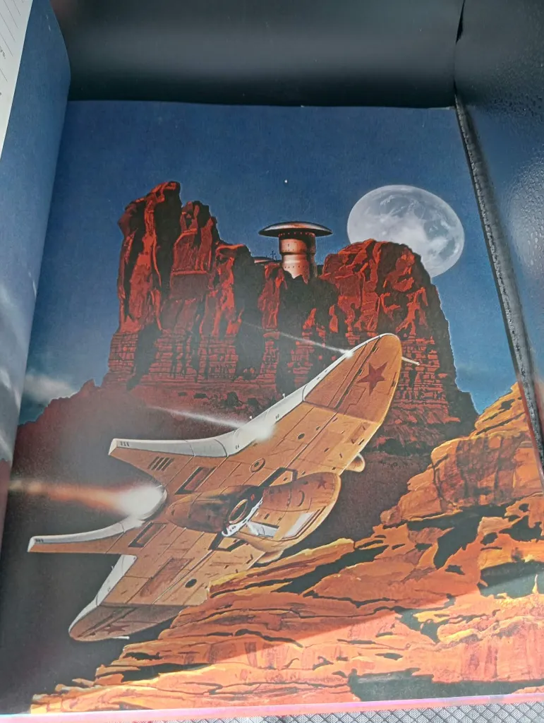 Franstalig boek Les Longs Courriers de l’Espace van Stewart Cowley, uitgegeven door Dargaud in 1981, zwarte omslag met rode ruimteschepen, kleurenillustraties en zwaar beschadigde rug