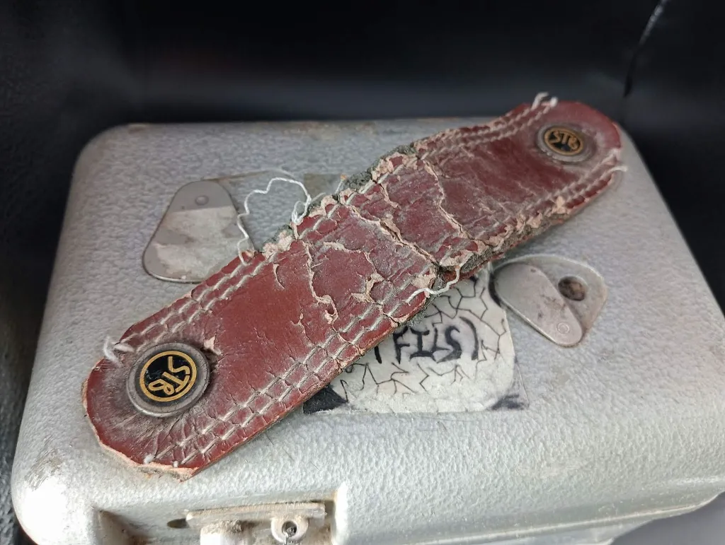 Vintage mechanical STB Swiss Made pigeon racing clock in hammered grey metal with white dial number 67992, side closure with metal seal and heavily cracked red leather handle